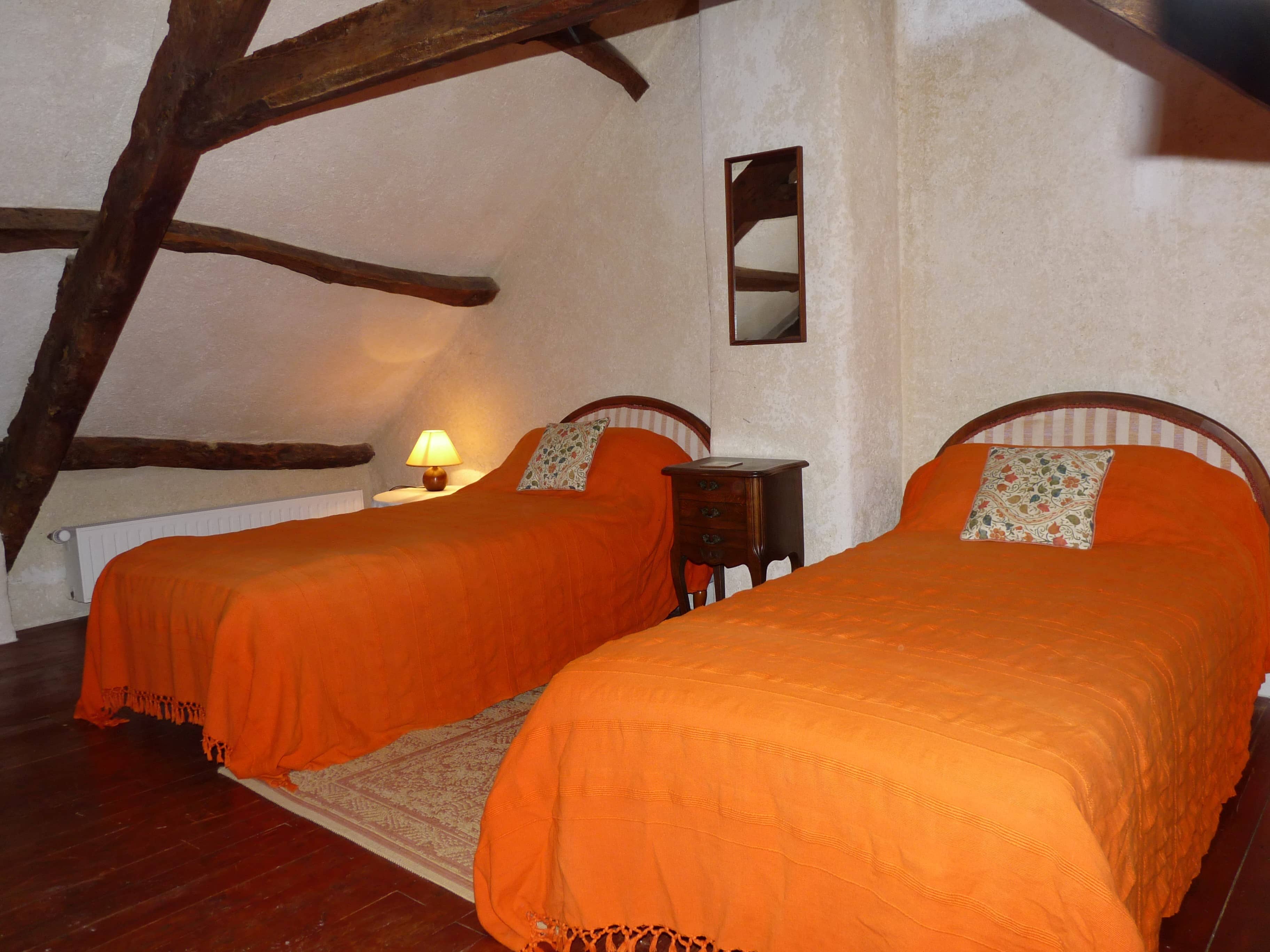 Spacious and comfortable bedroom of La Julerie cottage in Brittany, France, with a king-size bed, elegant rustic decor, a stone fireplace, and a panoramic view of the surrounding countryside. Perfect for a peaceful night's sleep after a day of sightseeing in the Brittany region.